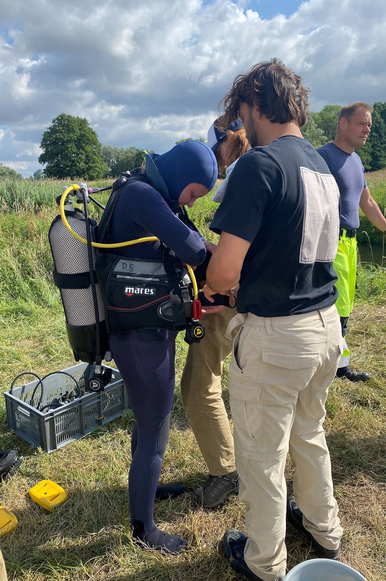 A person helps another putting on diving gear