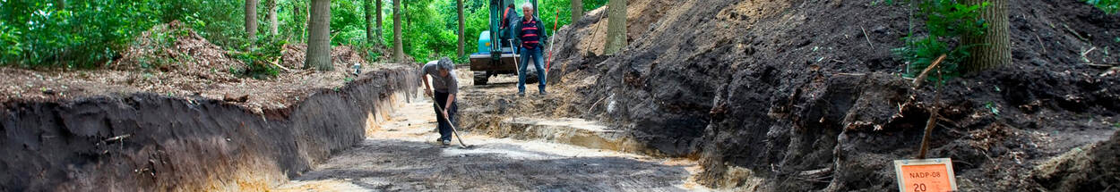 Twee mannen zijn bezig met archeologisch onderzoek in de bossen.
