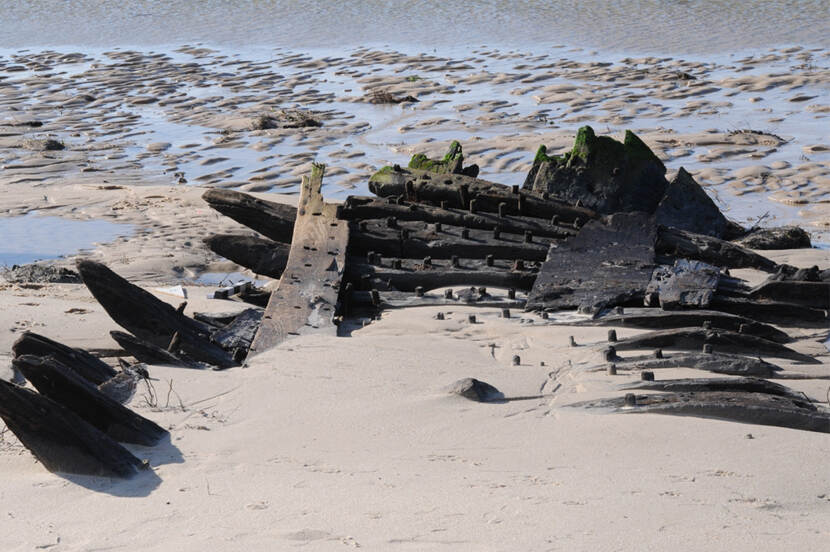 Part of the shipwreck lies in the sand.