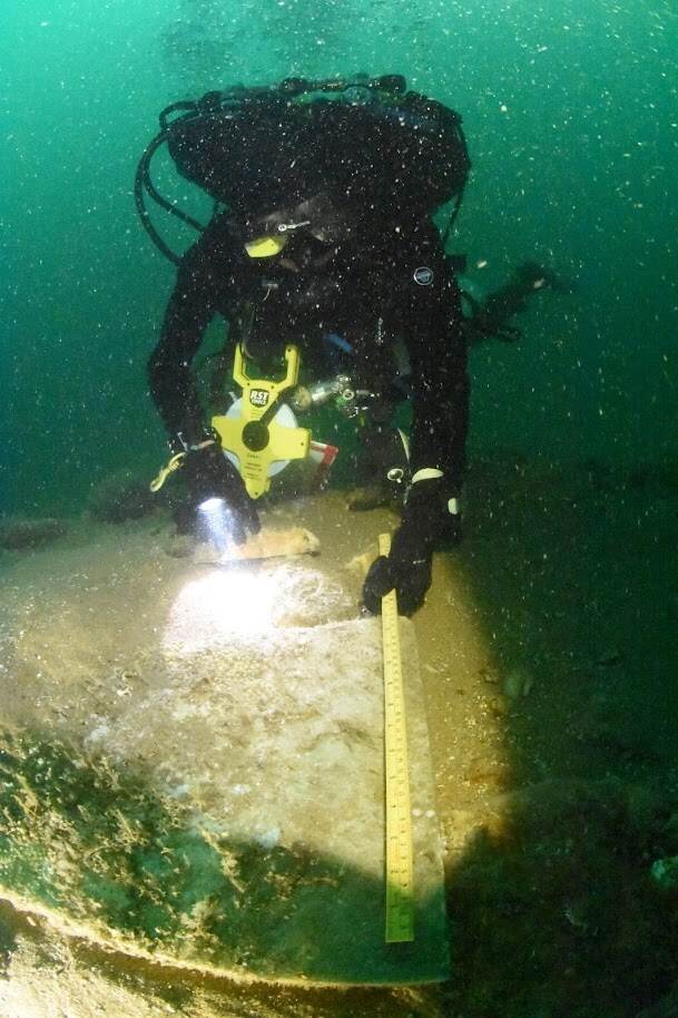 A diver is measuring the length of a marble tile.