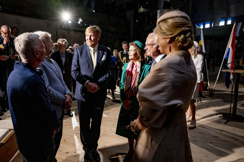 Koning Willem-Alexander in gesprek met een groep mensen tijdens de overhandiging van de scheepsbel